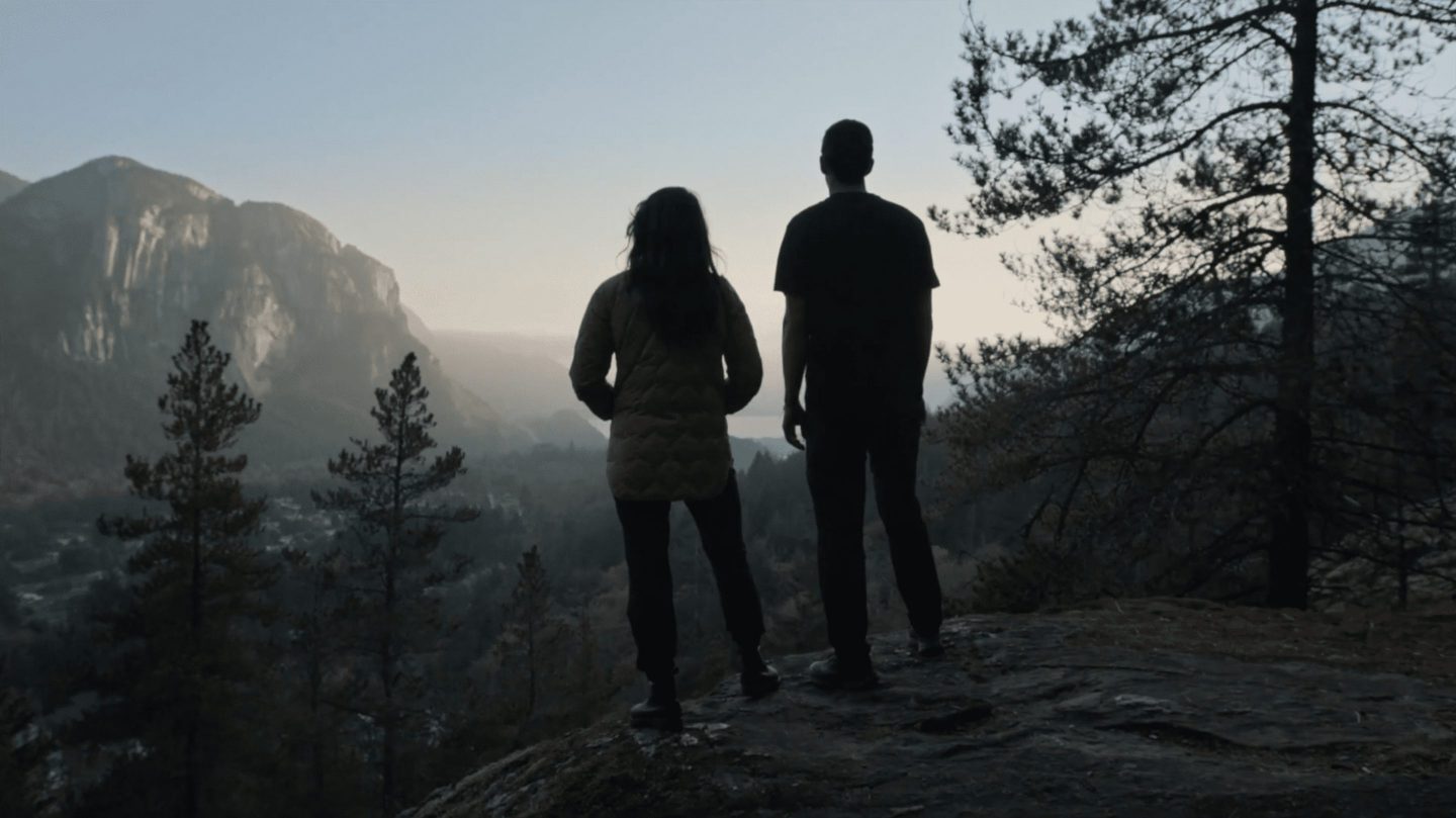 silhouettes of two figures against a mountainous sky range